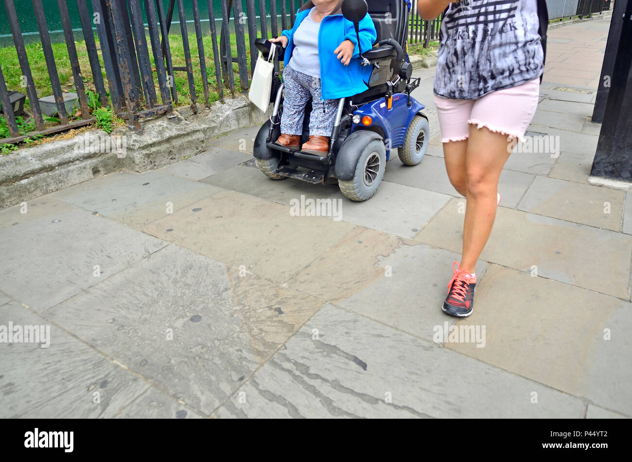 Donna disabile in una sedia a rotelle motorizzata con un grado corposo amico, Londra, Inghilterra, Regno Unito. Foto Stock