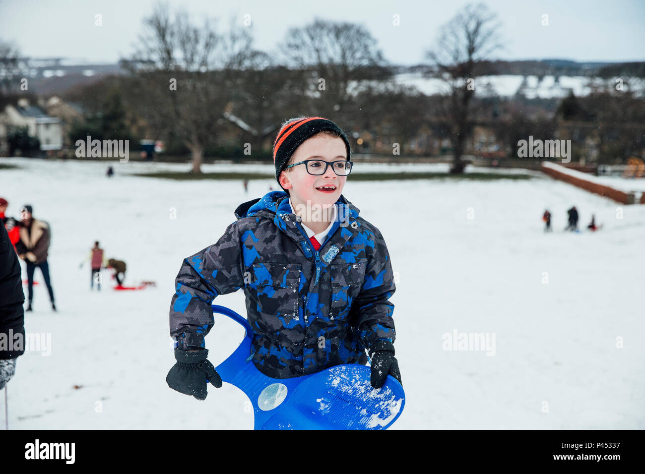 Little Boy è tornare indietro a piedi fino a Big Hill dopo la discesa in slittino nella neve. Foto Stock