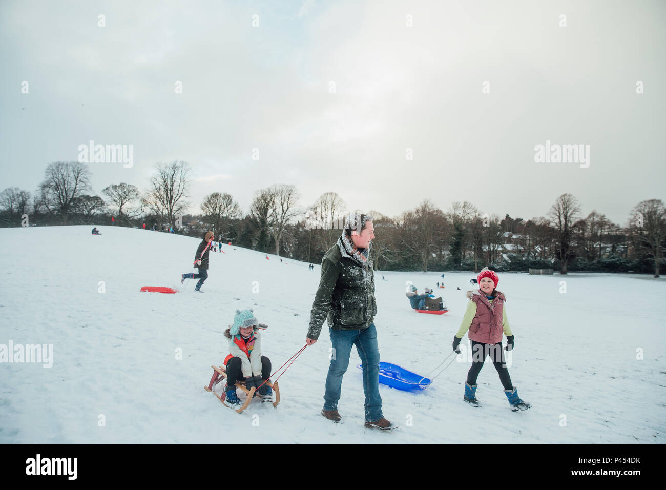 L uomo è fuori slittino sulla neve con le sue figlie. Foto Stock