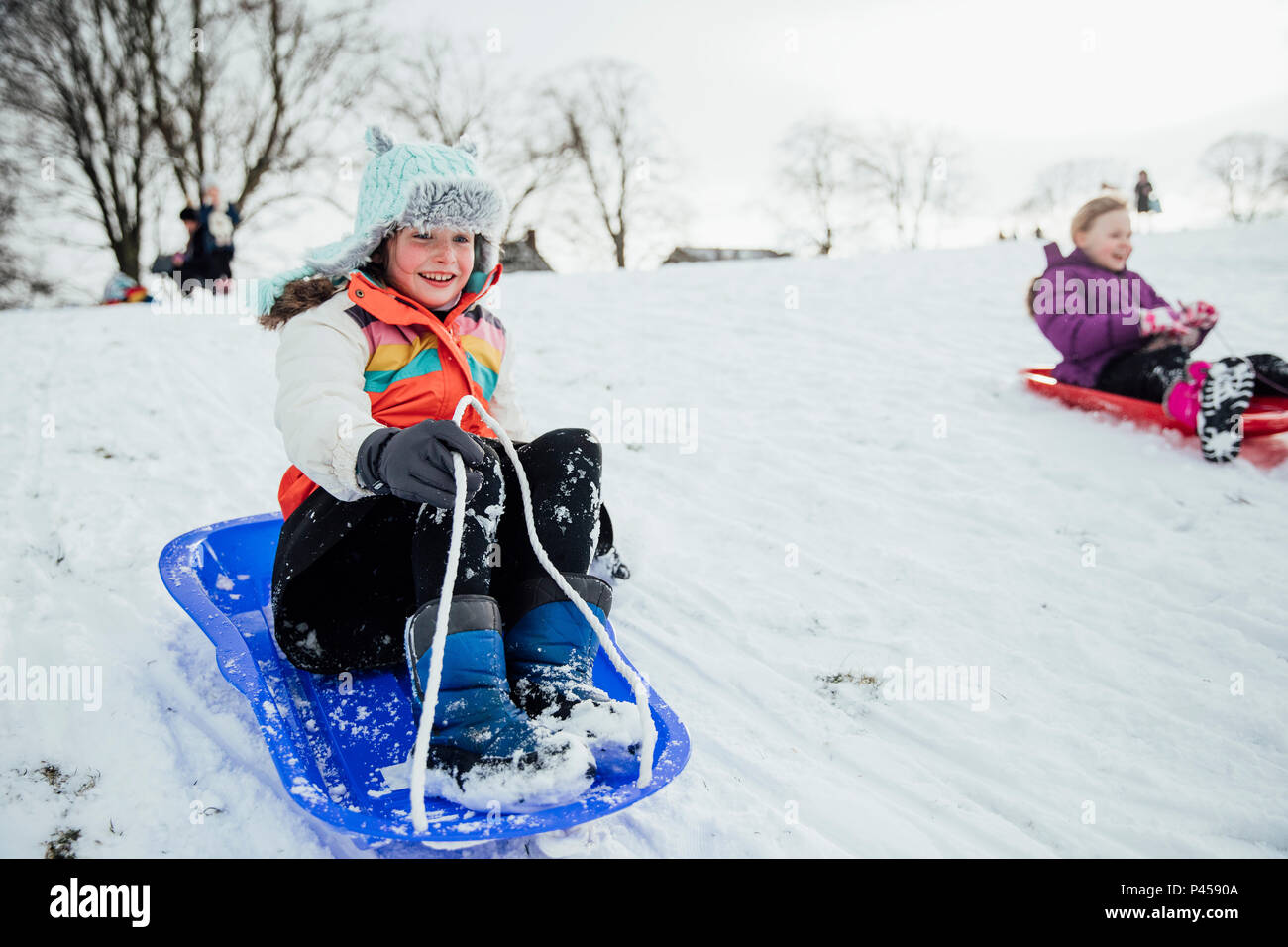 Immagine ravvicinata di una bambina su una slitta di neve in una gara della comunità. Foto Stock