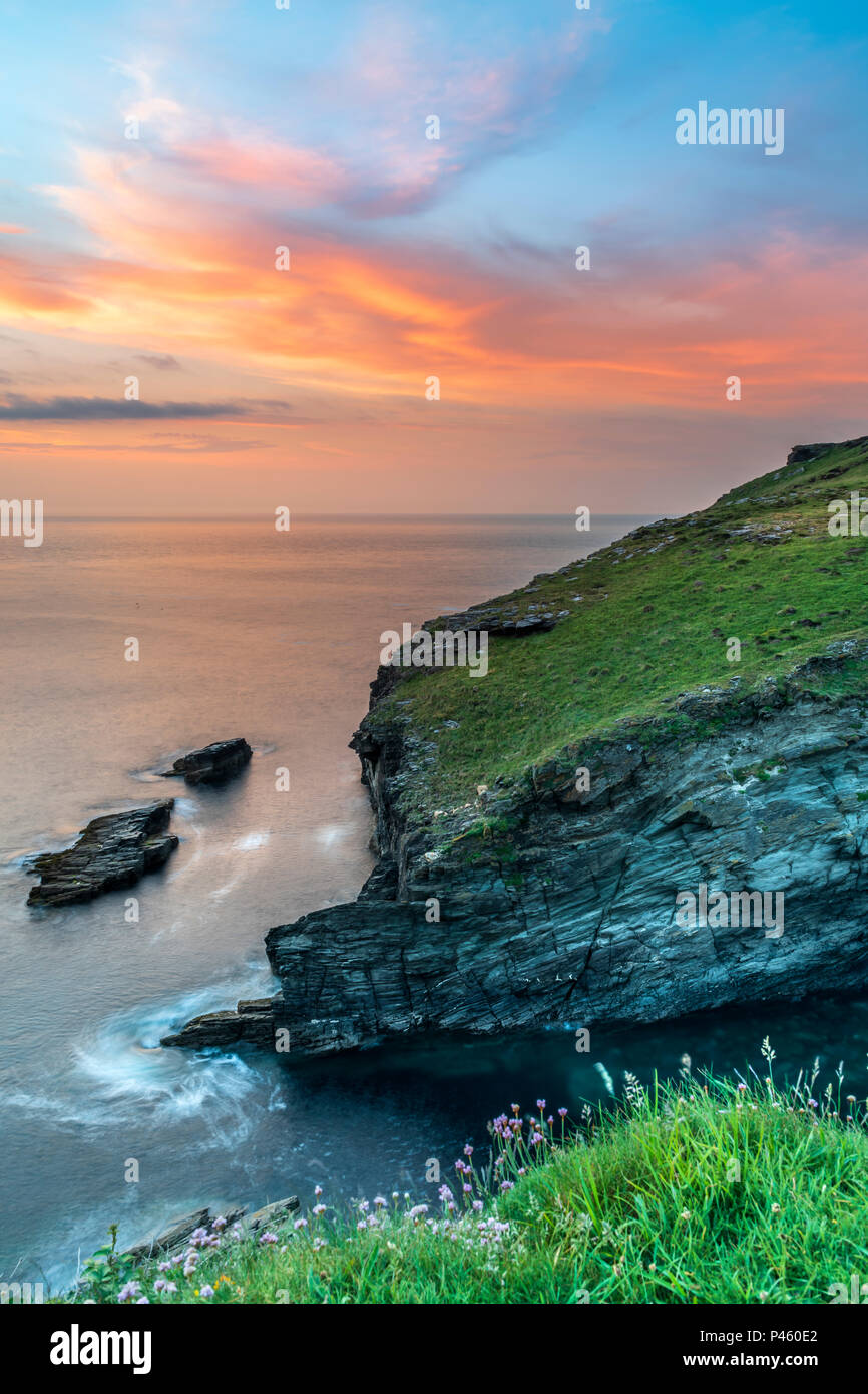 Dopo un giorno nuvoloso, il cielo scompare come il sole tramonta sul promontorio di Tintagel in Cornovaglia, con la previsione di impostare per il sole e docce in Foto Stock