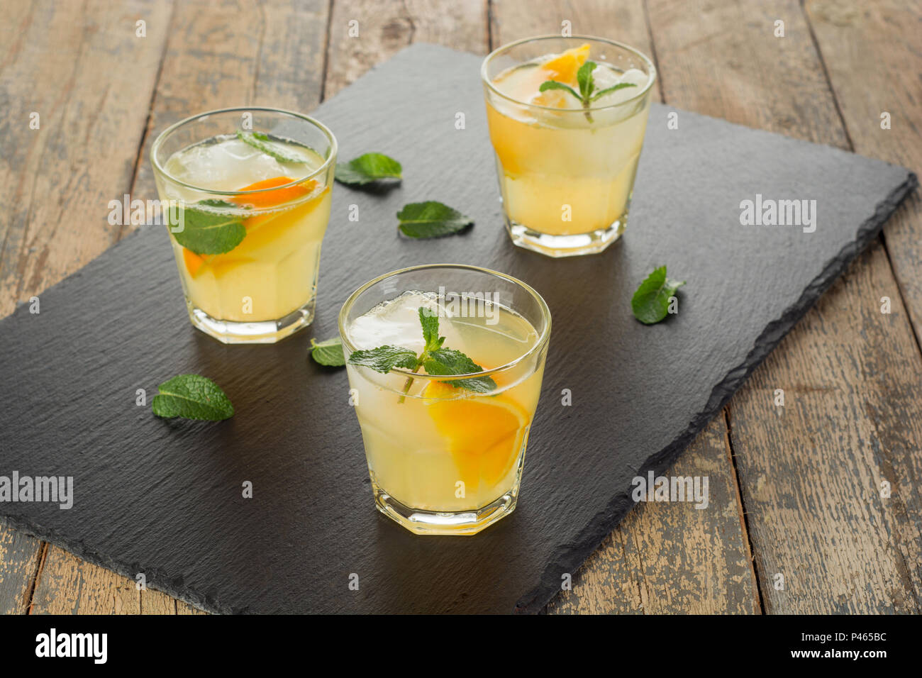 Cocktail. Succo di arancia con la menta e il ghiaccio su tavola in legno rustico Foto Stock