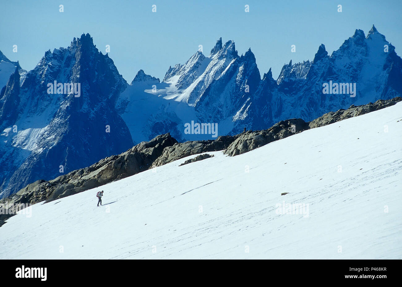 La figura di un alpinista solitario nelle Alpi francesi con le Aiguilles di Chamonix al di là Foto Stock