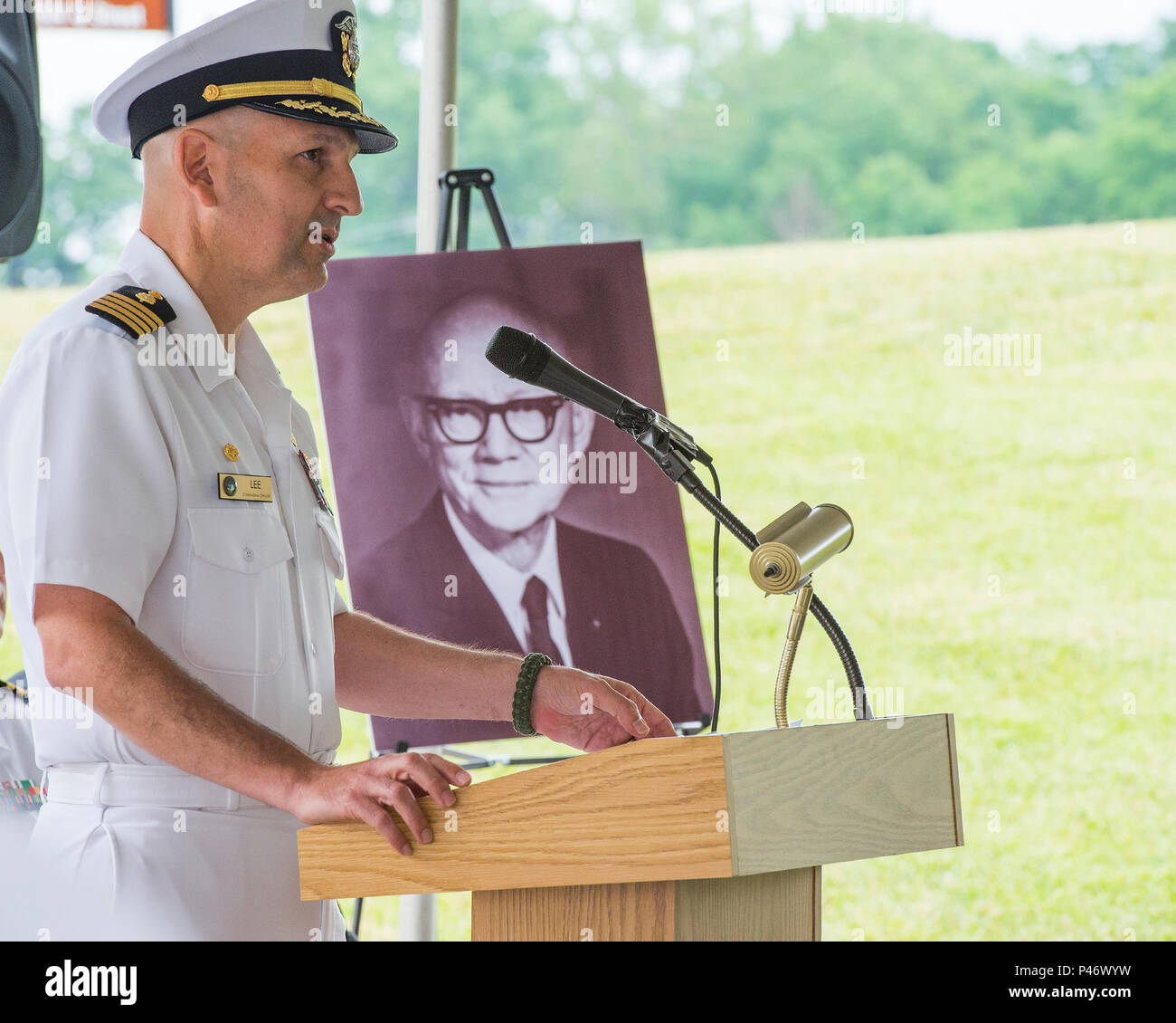 Capitano di marina Rees L. Lee, Naval Medical Research Unit Dayton comandante, parla alla cerimonia di completamento di marcatura del disorientamento del dispositivo di ricerca presso il nuovo capitano Ashton Graybiel accelerazione struttura di ricerca, 17 giugno 2016 su Wright-Patterson Air Force Base in Ohio. Un ritratto di Graybiel, che è stato il pioniere della ricerca sugli effetti di disorientamento sui piloti per la marina militare e la NASA, era sulla prominente visualizzato durante la cerimonia. (U.S. Air Force foto di R.J. Oriez/rilasciato) Foto Stock