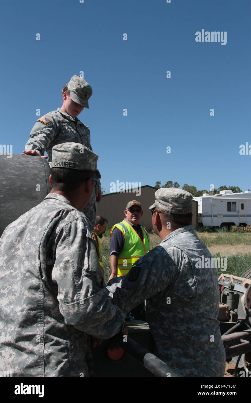 I soldati della Guardia Nazionale della 720th Transportation Company e del 615th Transportation Battalion consegnarono oltre 11.000 galloni d'acqua ai ranch vicino a Pohl Road nel nuovo Messico durante l'evacuazione del Dog Head Fire il 20 giugno 2016. La missione sostenne la risposta di emergenza contro gli incendi, utilizzando metodi improvvisati per riempire le troughe dei cavalli e assistere le comunità locali. Le unità coinvolte includevano personale dell'esercito e dell'aeronautica, con la partecipazione di forze di sicurezza, polizia militare e elementi della Guardia nazionale statale per sostenere le operazioni di evacuazione civile e di supporto. Foto Stock