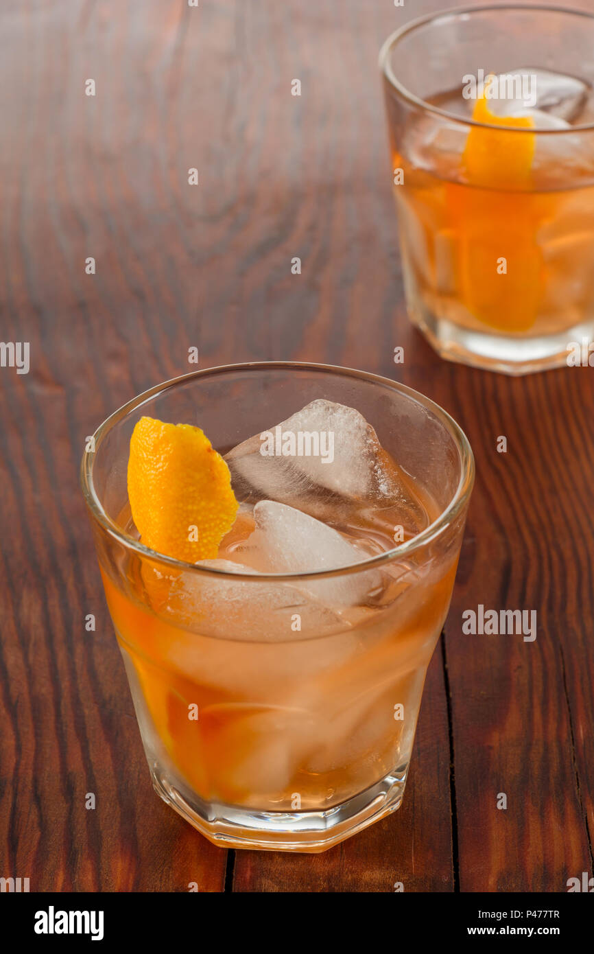 Primo piano di vetro negroni cocktail decorata con gli agrumi sul legno scuro dello sfondo. Foto Stock