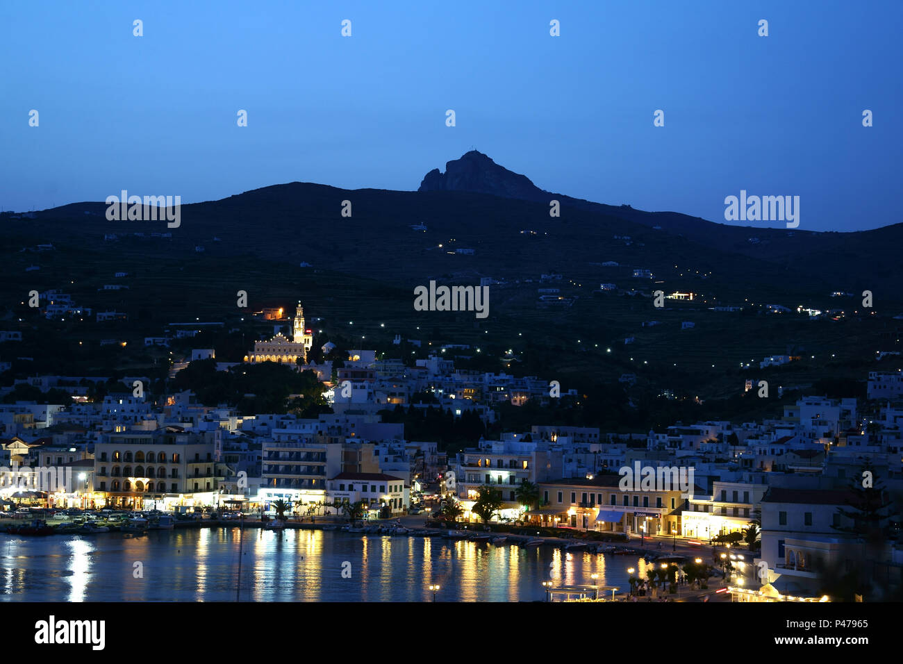 Città Tinos di notte con Exombourgo montagna, isola di Tinos, Cicladi Grecia Foto Stock