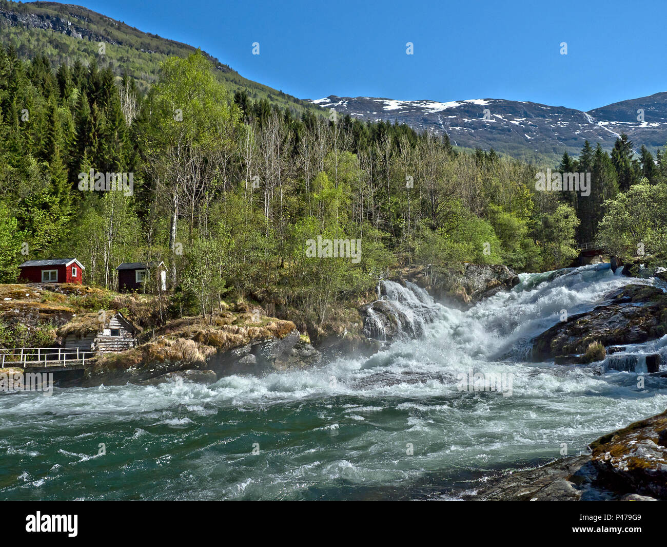 Norvegia, nei pressi di fiordi, nei pressi di Hellesylt, fiume con forte flusso e potenti cascate multiple, luce verde primavera, neve sulle cime dei fissaggi Foto Stock