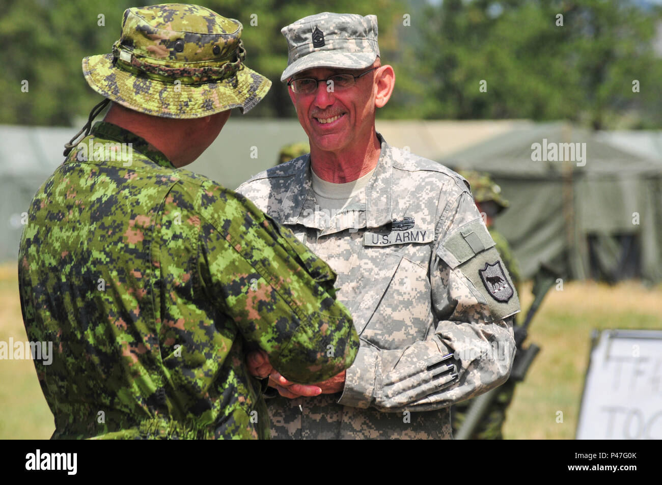 Esercito canadese Col. John Conrad, sinistra, comandante del 41 Brigata canadese gruppo soddisfa con U.S. Army Sgt. Il Mag. George Arends, South Dakota Guardia nazionale, Task Force 41 Camp Sergente Maggiore come parte del Golden Coyote in avanti su una base operativa Custer, Custer, S.D., 15 giugno 2016. Il Golden Coyote è un esercizio a tre-fase, scenario di esercizio di condotta condotta in Black Hills del Sud Dakota e Wyoming, quali comandanti permette di concentrarsi sulla missione requisiti essenziali per lo svolgimento delle attività e le attività del guerriero e punte di battaglia. (U.S. Esercito foto di Spc. Robert West /rilasciato) Foto Stock