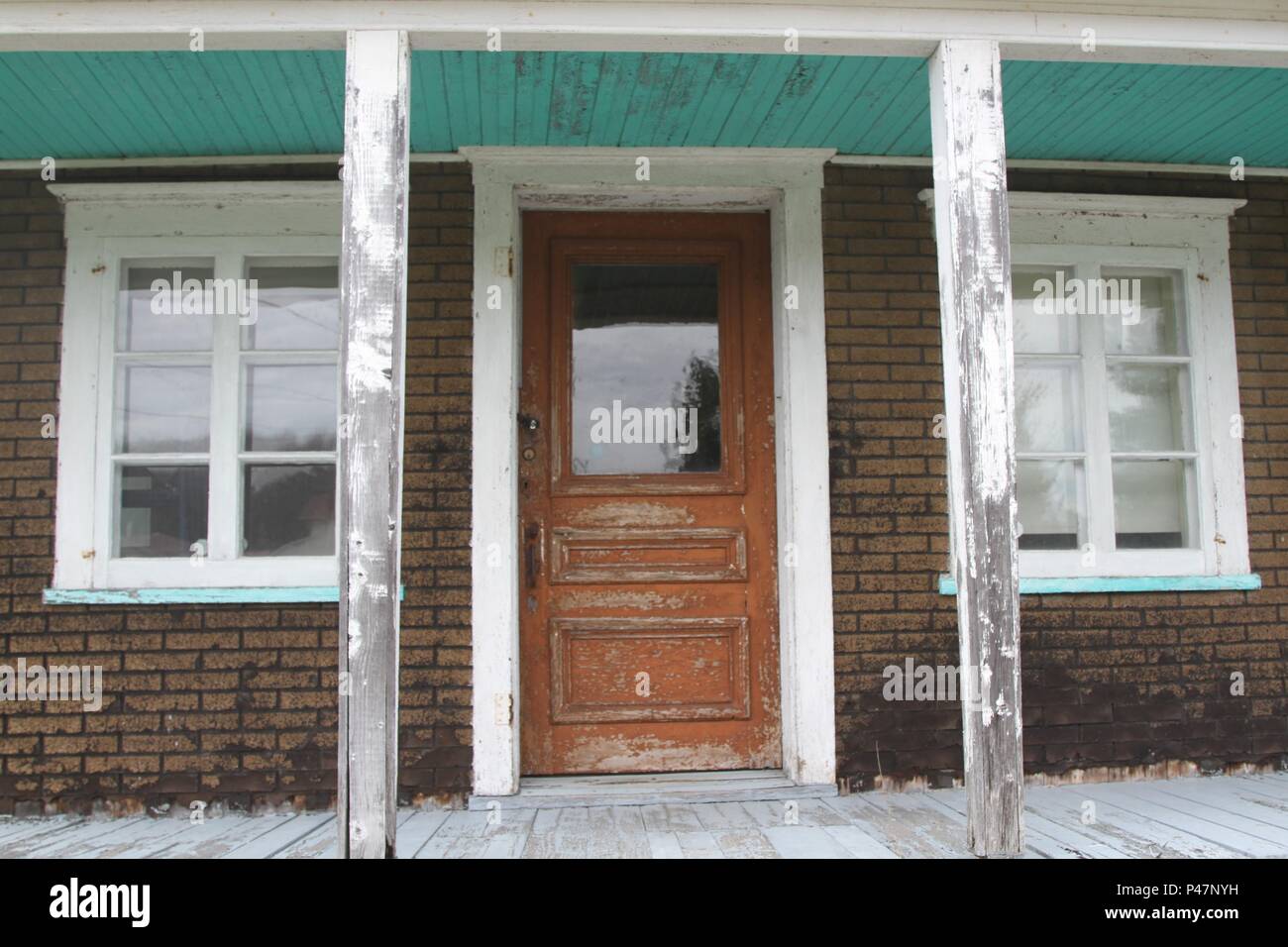 Vecchia casa abbandonata con una piastrella carta pareti in mattoni e arrugginita vuota,tetto metallico Foto Stock