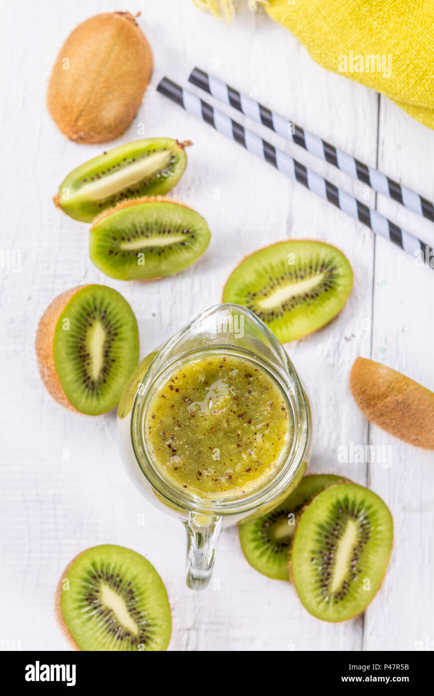 Sani e freschi Frullato di kiwi in vetro su uno sfondo di legno. Focus su smoothie in una caraffa. Foto Stock