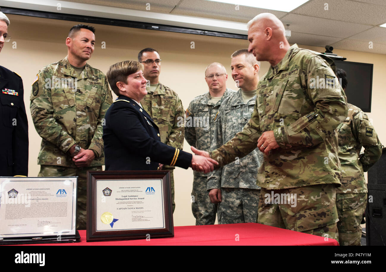 I membri dell'ottantesimo il comando di formazione presso la sede centrale della società a guardare come il comando Chief Warrant Officer Randy L. Schriver, l'ottantesimo TC del comando del chief warrant officer, si congratula con il cap. Tanya Mayes, un diritto amministrativo e giustizia militare attorney assegnato all'ottantesimo TC, dopo aver ritirato il capitano della Marina Dwain Alexander, membro dell'American Bar Association di assistenza legale per il personale militare Distinguished Service Award comitato, presentato Mayes con la lampada 2015 premio in occasione di una cerimonia presso il cacciatore Holmes McGuire VA Medical Center di Giugno 10, 2016. Mayes è stato riconosciuto per la conduzione di un ef Foto Stock