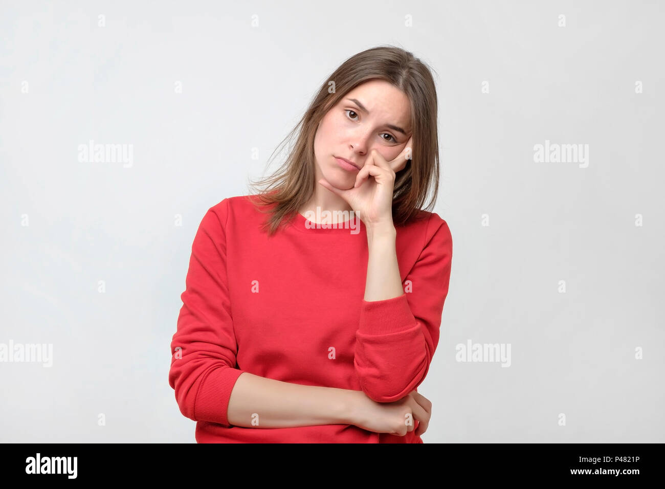 Bella donna caucasici in maglione rosso è stanco o annoiato. Lei non desidera che per motivi di lavoro o di studio. Beed a riposo. Debiti di credito concetto Foto Stock