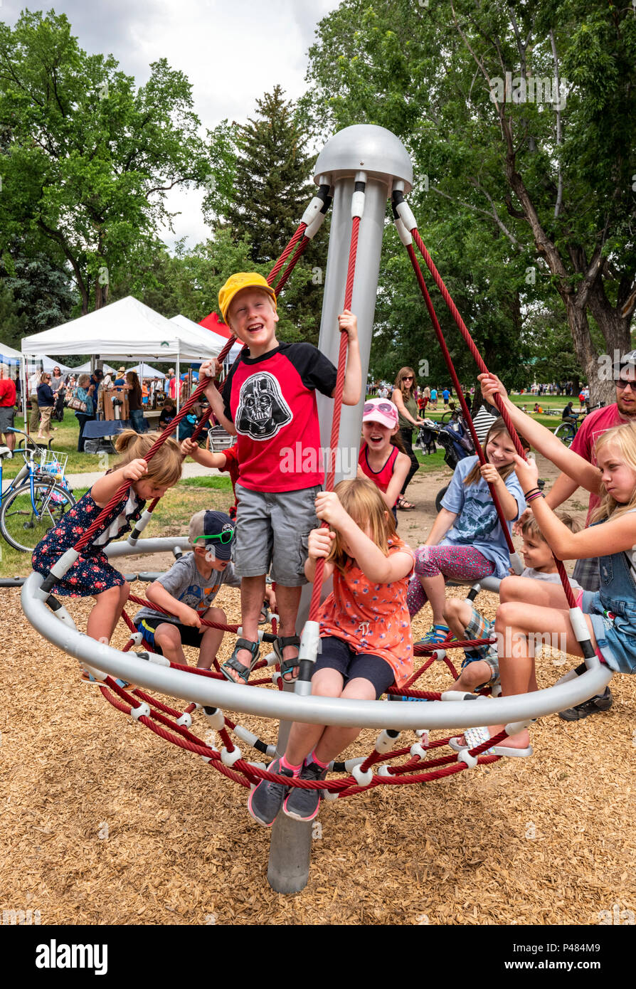 I bambini la filatura sul parco giochi merry-go-round; Salida; Colorado; USA Foto Stock