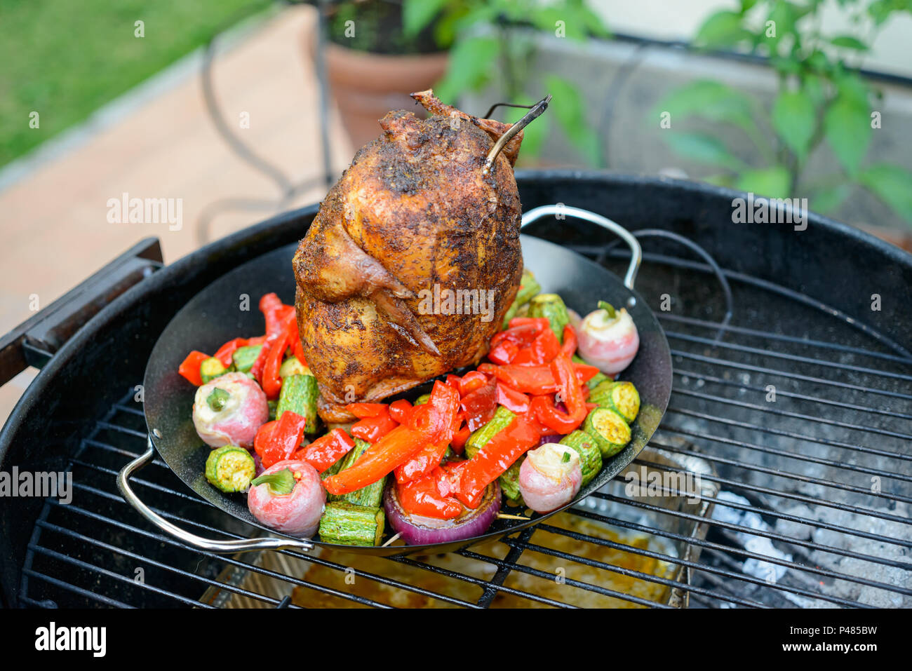La cottura alla griglia una lattina di birra pollo in un barbecue, con  paprika rub e sonda di temperatura, verdure in padella Foto stock - Alamy