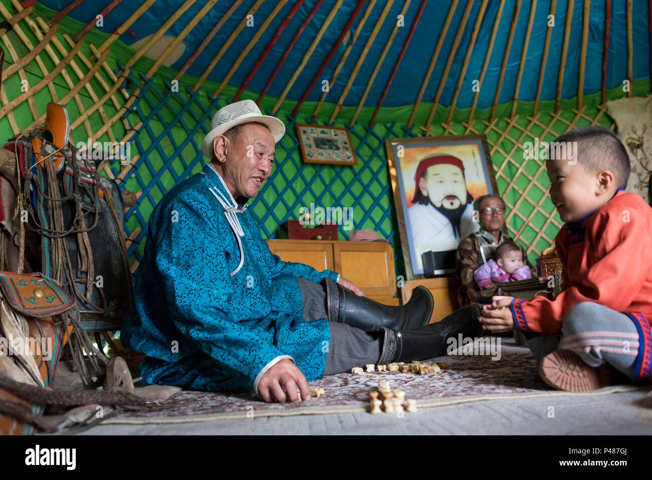 Padre e figlio il gioco del gioco con le ossa di animali all'interno della loro estate yurt, Zhenglanqi Wuyi, Mongolia interna Foto Stock