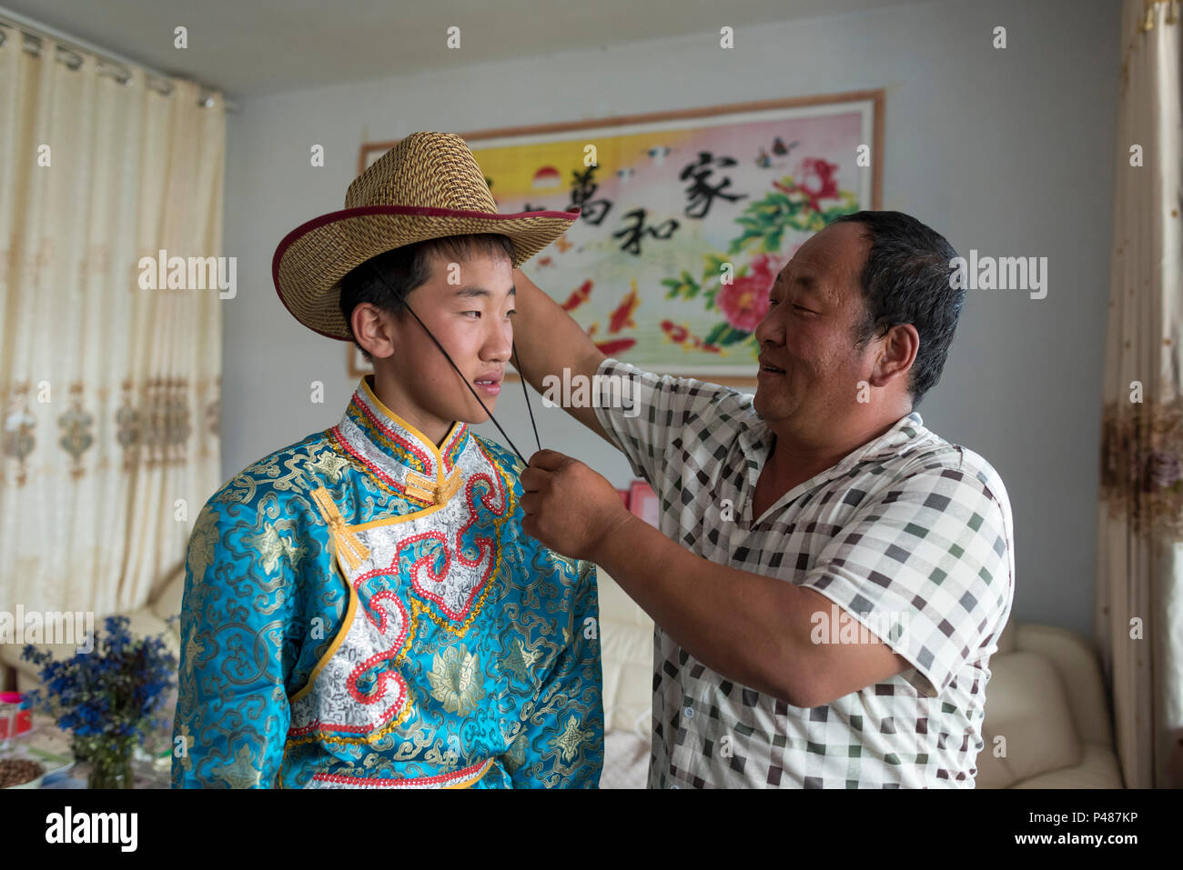 Un padre aiuta a vestire il suo figlio, un giovane cavaliere mongolo, Duolun, Mongolia Interna, Cina Foto Stock