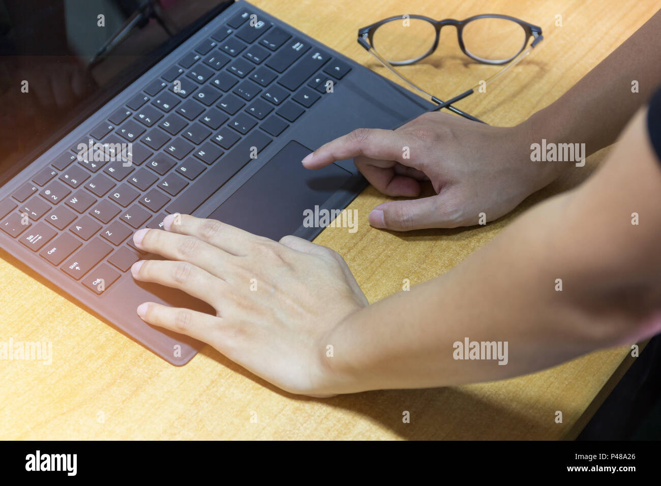 Imprenditore mani lavorando su laptop moderno computer su area di lavoro con scrivania in legno, effetto luce messa a fuoco selezione. Foto Stock