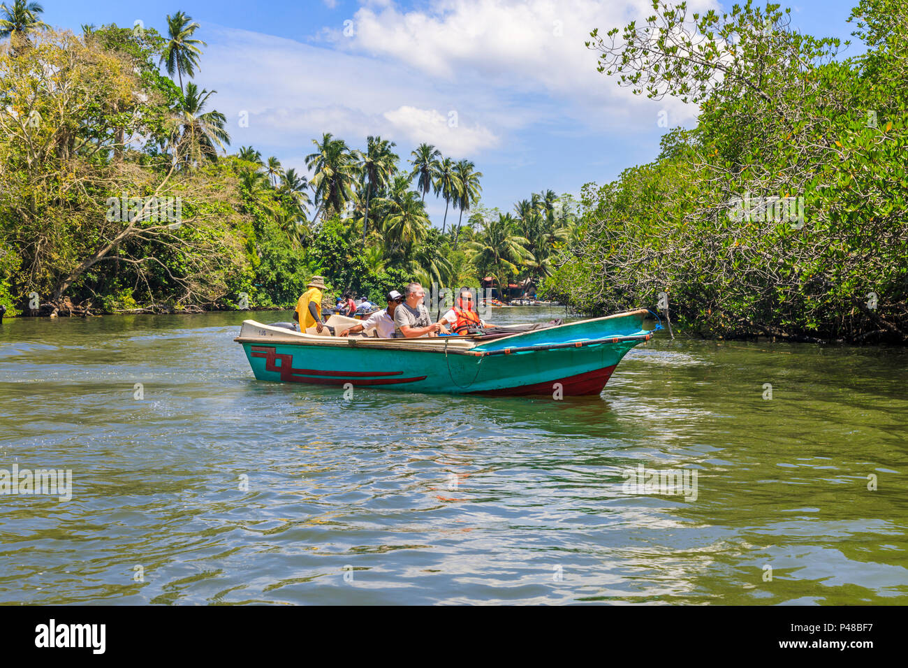 Turisti che si godono un viaggio in una piccola barca e viste di giungla tropicale palme e natura, Madu River, Madu Ganga zone umide, a sud-ovest dello Sri Lanka Foto Stock