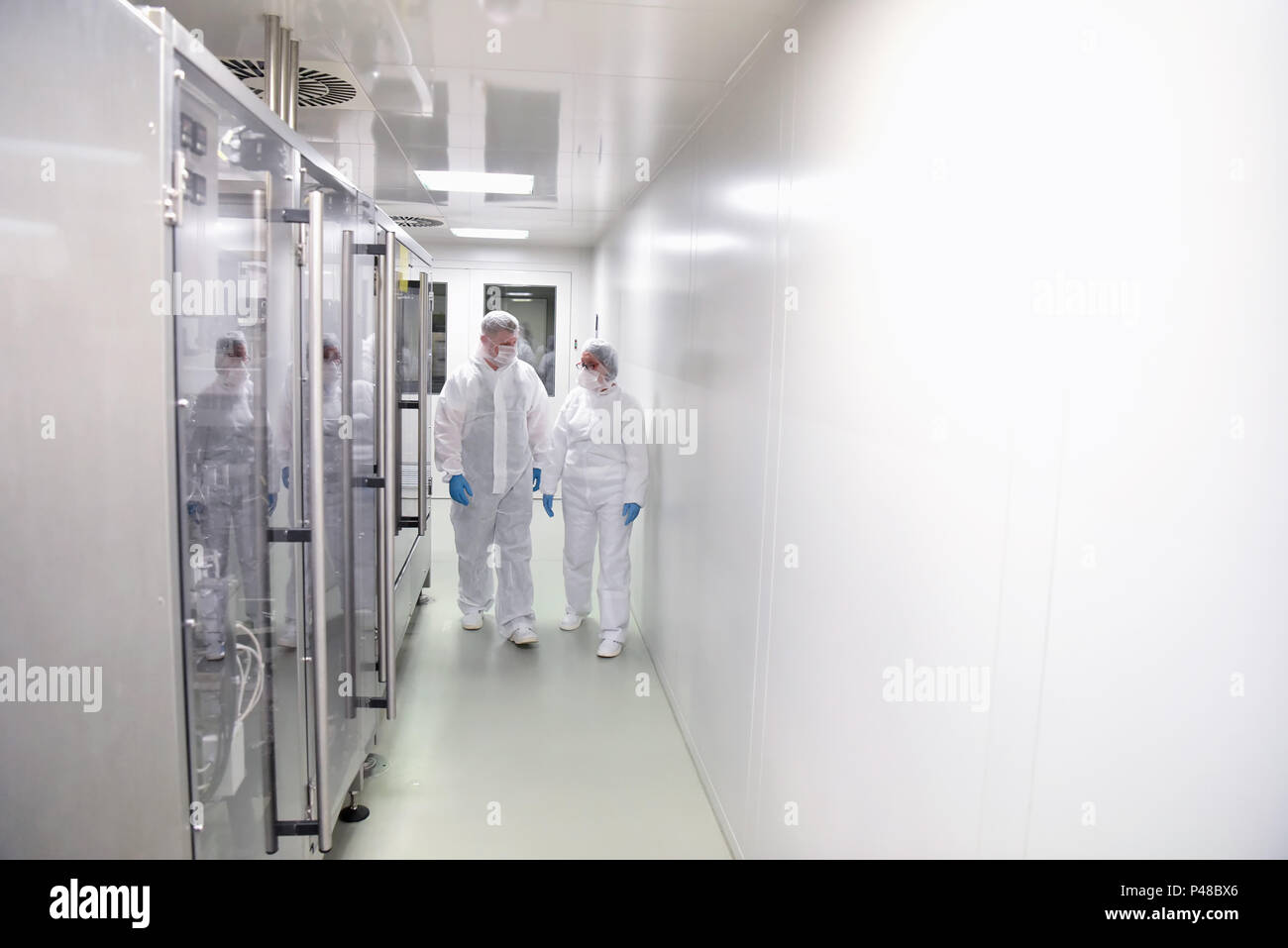Gruppo di lavoratori in abbigliamento protettivo in una camera sterile di una fabbrica di onore e lo sviluppo di farmaci Foto Stock