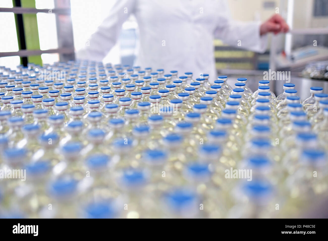 Riempimento e produzione di farmaci in un prodotto farmaceutico nastro trasportatore con bottiglie e un lavoratore Foto Stock