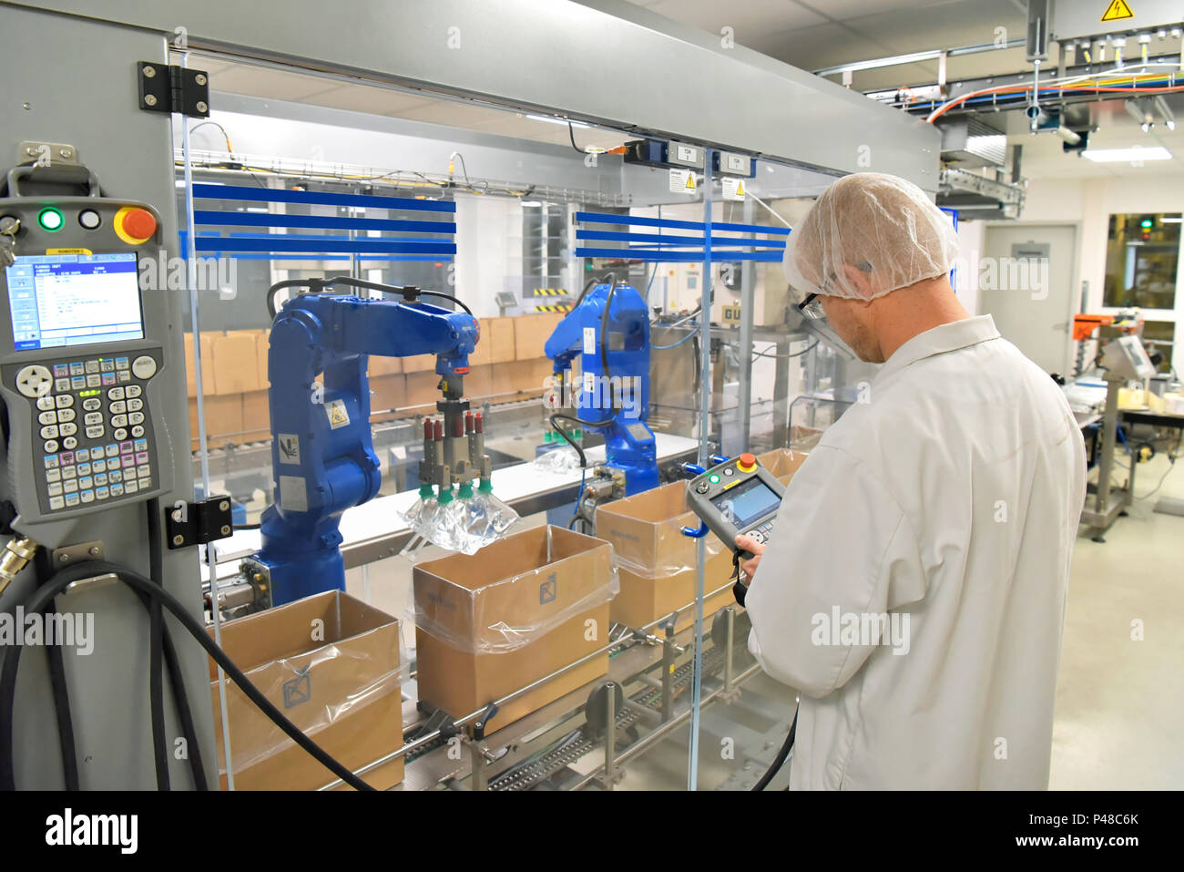 Nastro trasportatore lavoratore opera un robot che trasporta i sacchetti di insulina - moderno stabilimento per la produzione di medicinali nel settore sanitario Foto Stock