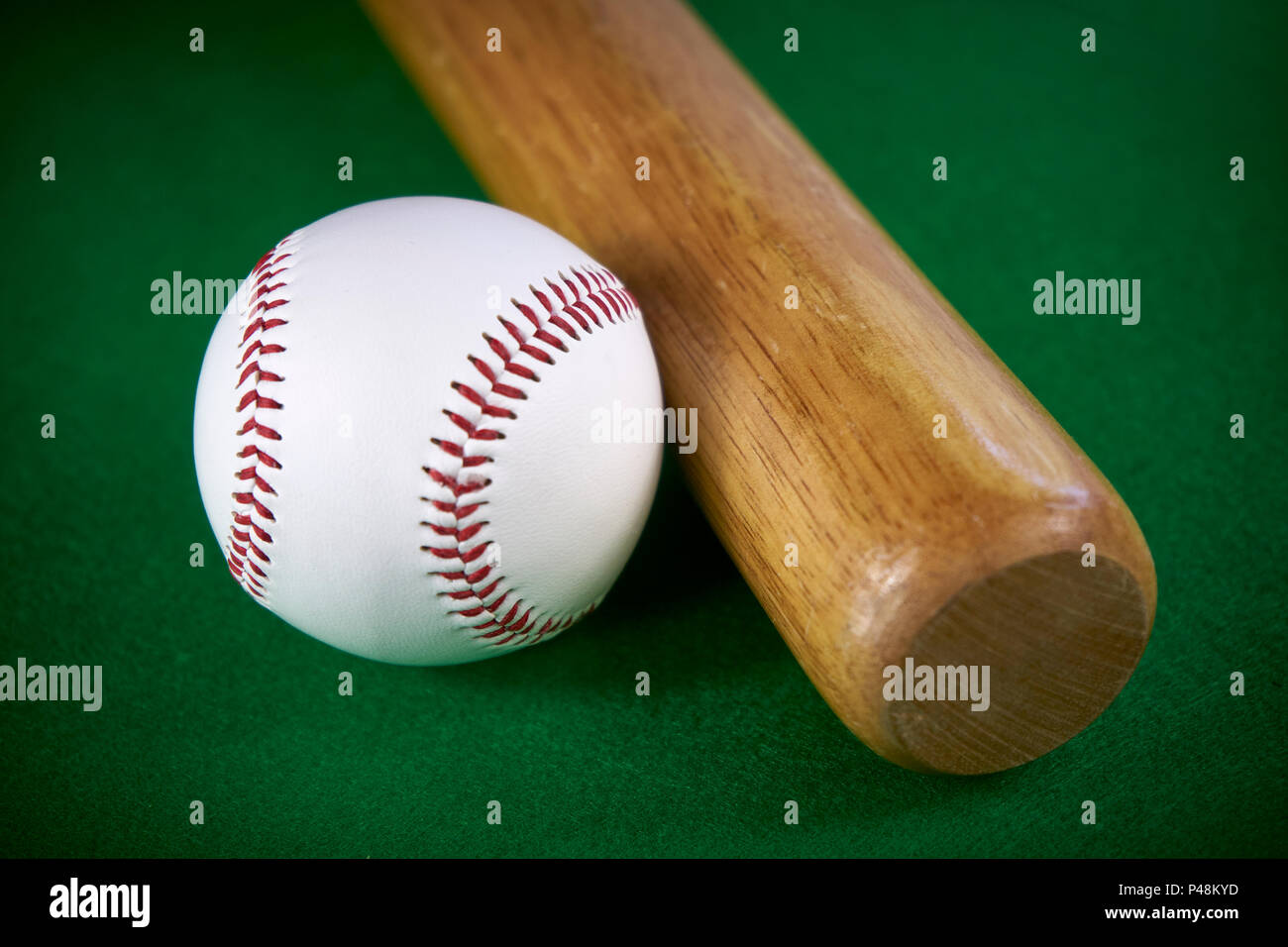 Bianco palla da baseball e la mazza di legno isolata sul feltro verde sullo sfondo Foto Stock