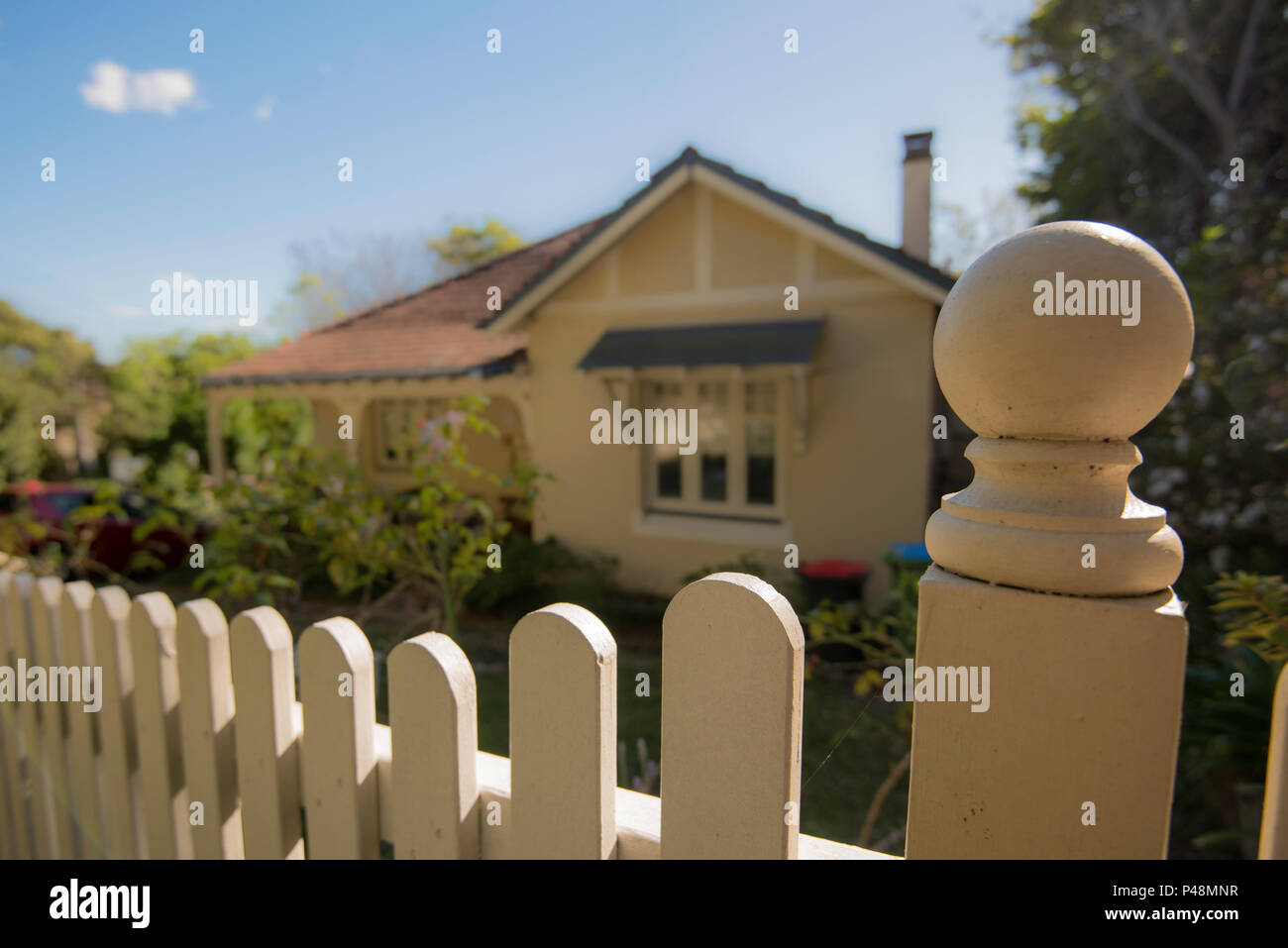 Un legname Picket Fence chiudere in primo piano con un dipinto di federazione home sfocati in background Foto Stock