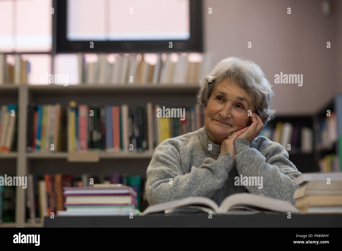 Senior donna sorridente in libreria Foto Stock