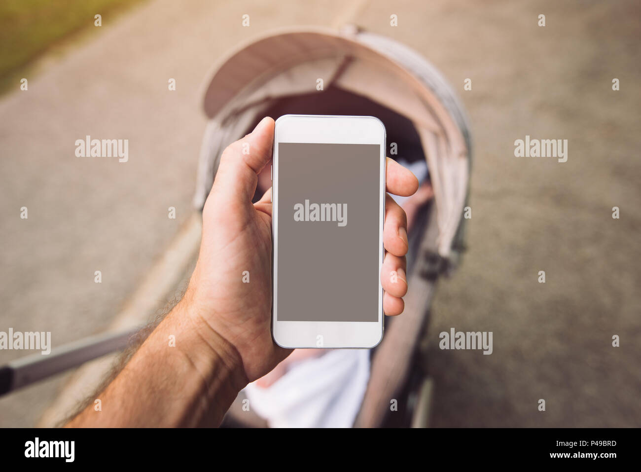 Il telefono è più interessante di bambino nel passeggino, smart phone con vuoto mock up schermo in mano maschio Foto Stock