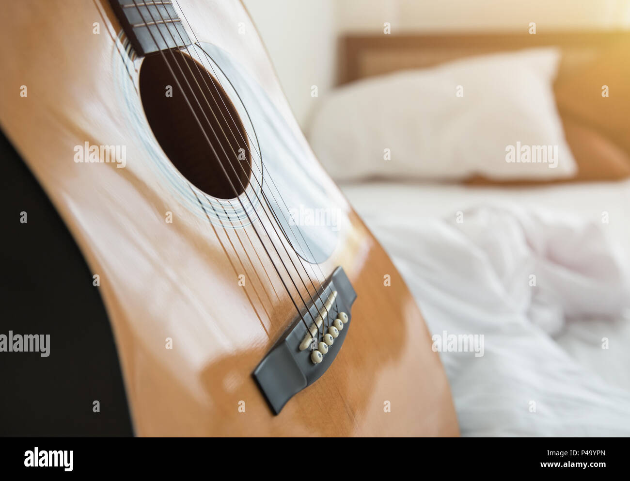 La musica in camera da letto il concetto di mattina. la chitarra con letto bianco sullo sfondo. Foto Stock