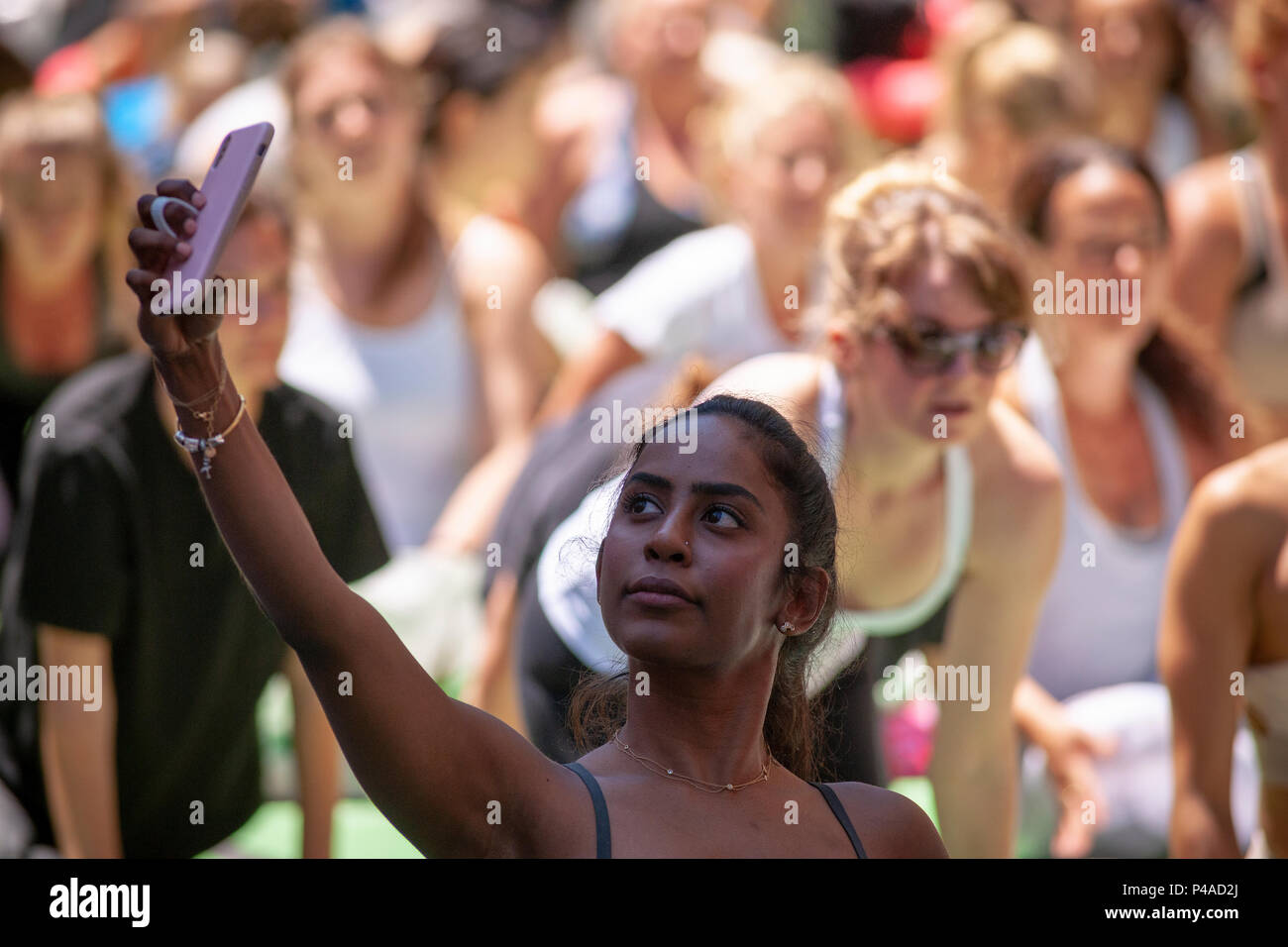 Un partecipante fa un "yoga selfie" in Times Square a New York il primo giorno di estate, Giovedì 21 Giugno, 2018. La 16th Annual Solstice in Times Square, 'Mind oltre follia", sponsorizzato da American Eagle Outfitters' marchio athleisure Aerie si estende il yogi' capacità di bloccare il rumore e il disordine visivo che li circondano nel crocevia del mondo. Il primo giorno di estate è stata dichiarata la Giornata Internazionale di Yoga dalle Nazioni Unite. (© Richard B. Levine) Credito: Richard Levine/Alamy Live News Foto Stock