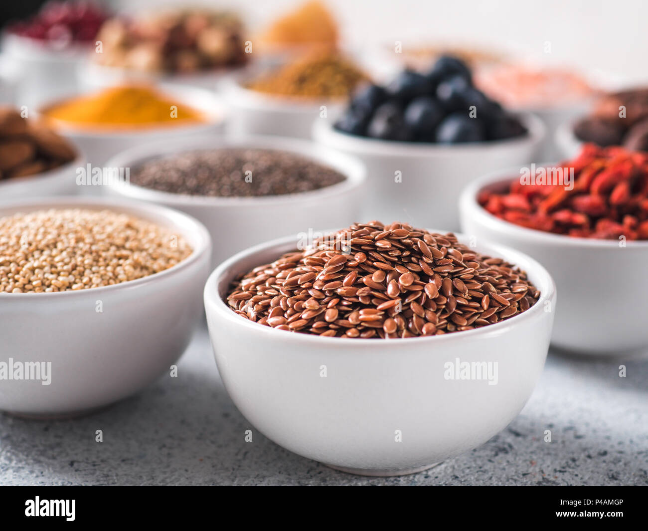 Lino sseds in piccola ciotola bianco e altri superfoods su su sfondo grigio Sfondo concreto. Messa a fuoco selettiva. Diversi ingredienti superfoods.Concetto e illustrazione per la super e detox food Foto Stock