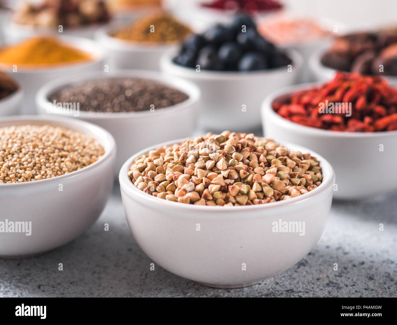 Materie verde Grano saraceno in piccola ciotola bianco e altri superfoods sullo sfondo. Messa a fuoco selettiva. Superfoods diversi ingredienti. Concetto e illustrazione per la super e detox food Foto Stock