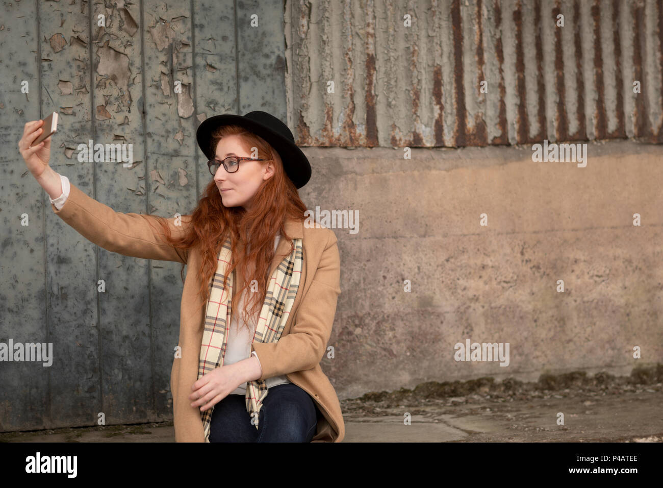 Donna prendendo selfie con telefono cellulare su un marciapiede Foto Stock