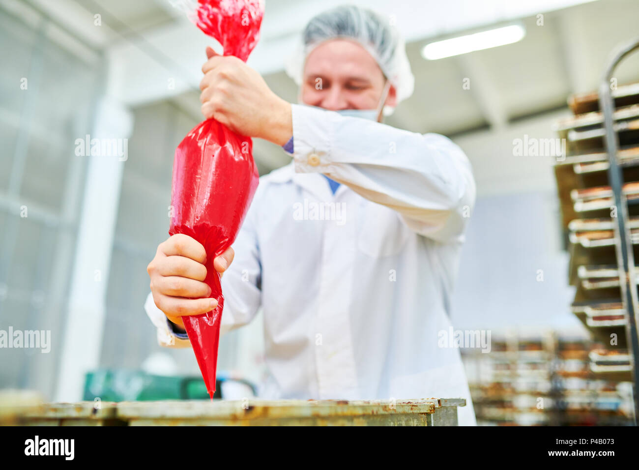 Pasticcere con glassa sacchetto in fabbrica Foto Stock