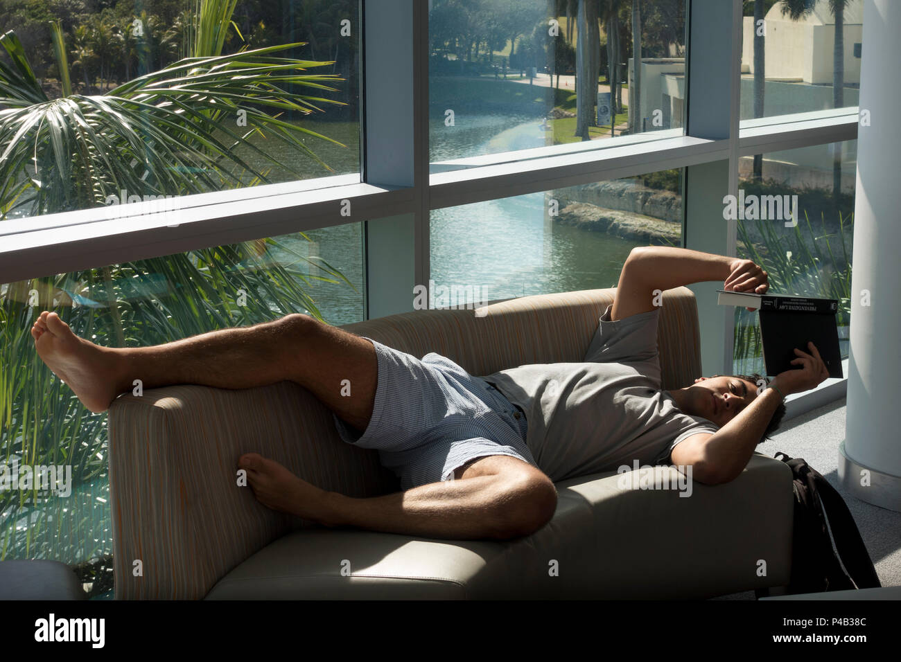 Studente legge libro mentre posa sul divano in Sun presso la University of Miami, Florida, Student Union. Foto Stock