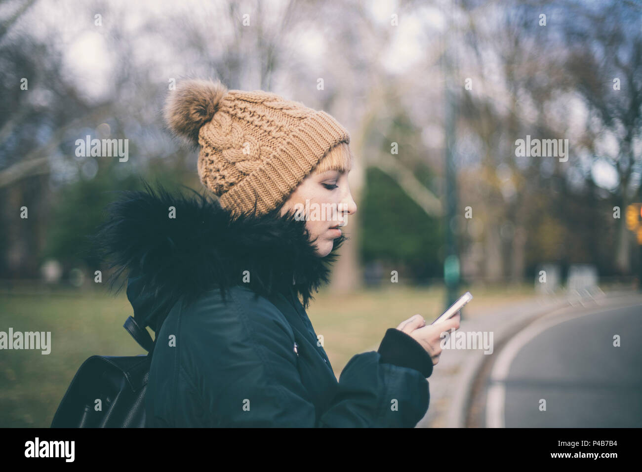 Donna che guarda al suo telefono cellulare in central park in inverno Foto Stock