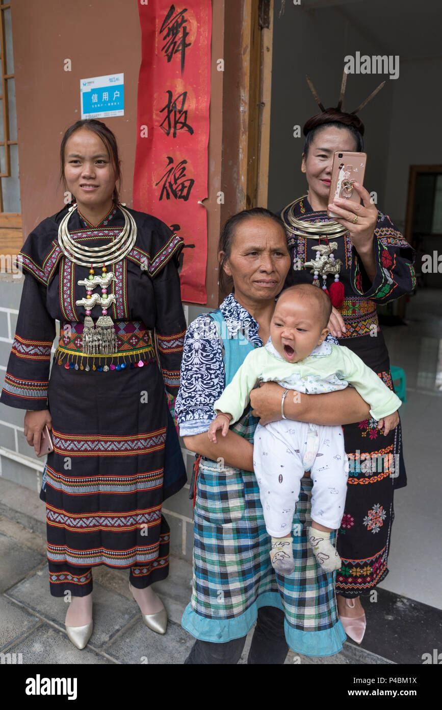 Multi famiglia generazionale in costumi tradizionali e collane argenteo, Yao minoranza etnica village, Maolan Lu, Libo, Quizhou Provincia, Cina Foto Stock