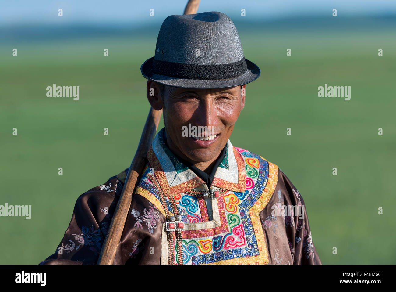 Vestite nel tradizionale costume mongolo, un cavaliere controlla la sua mandria, Mongolia Interna, Cina Foto Stock