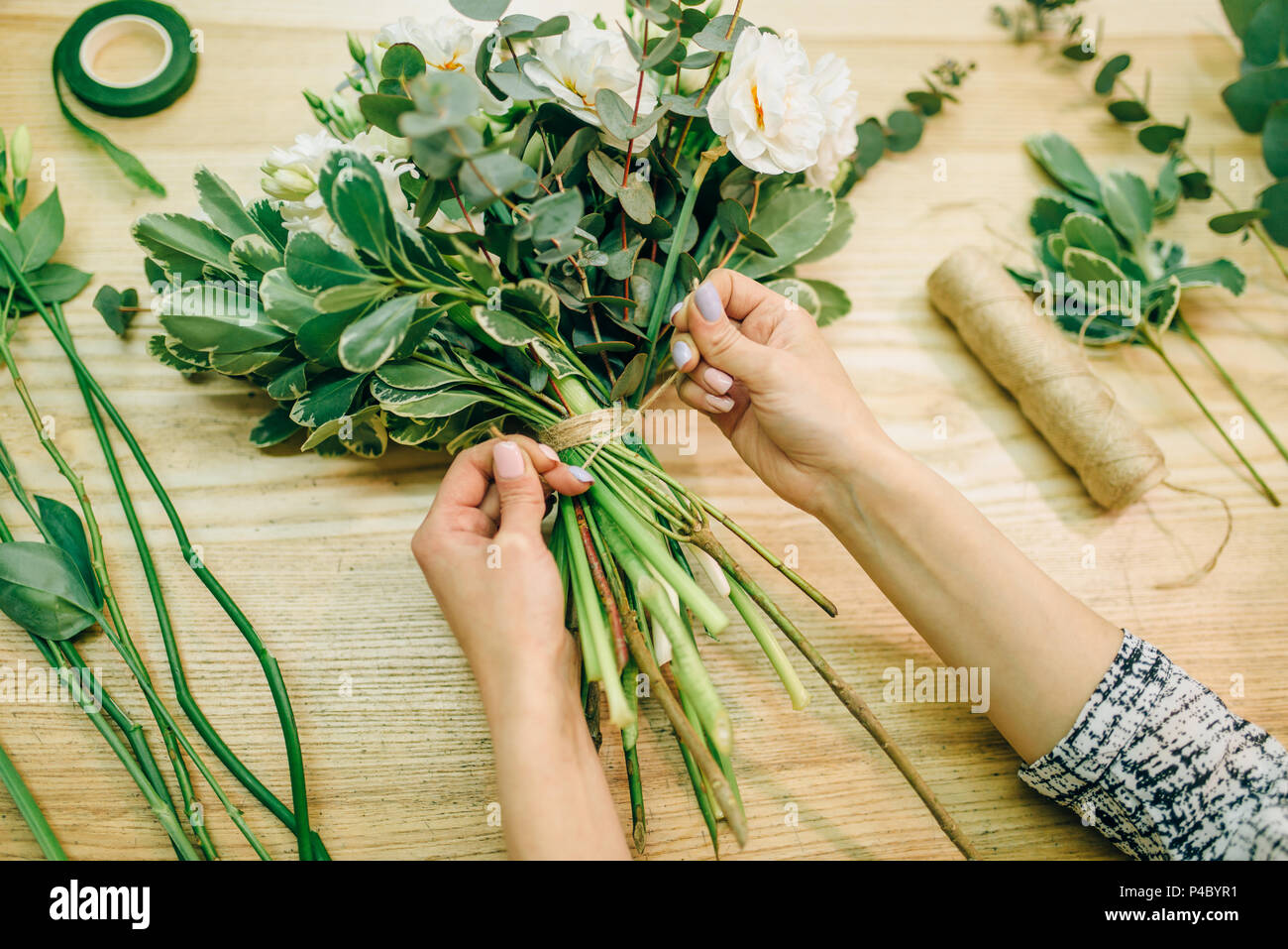 Fioraio cravatte un nastro su un mazzo di fiori Foto Stock