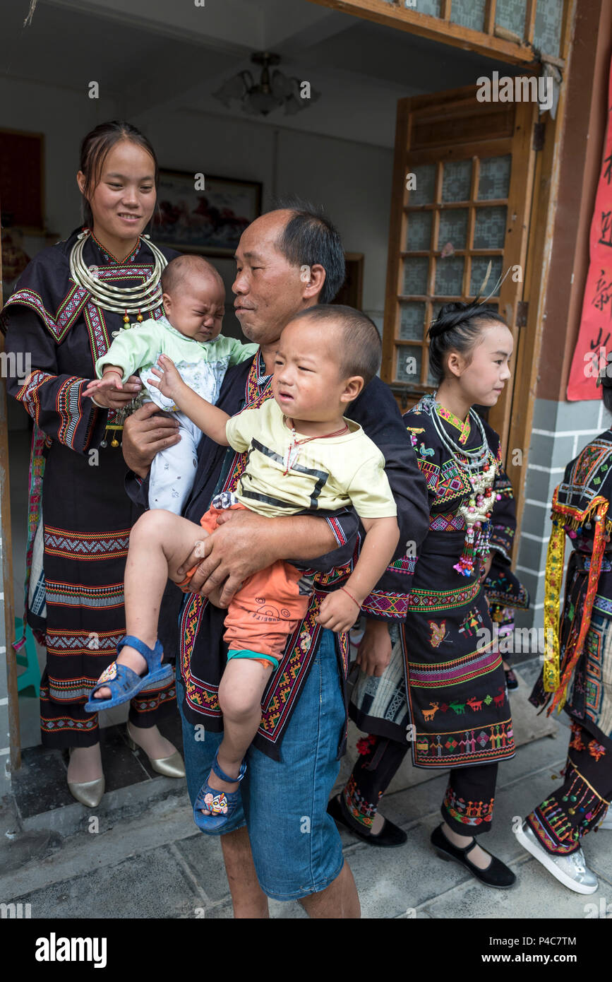 Nonna, spostando i neonati e padre in costumi tradizionali, Yao minoranza etnica village, Libo, Guizhou, Cina Foto Stock