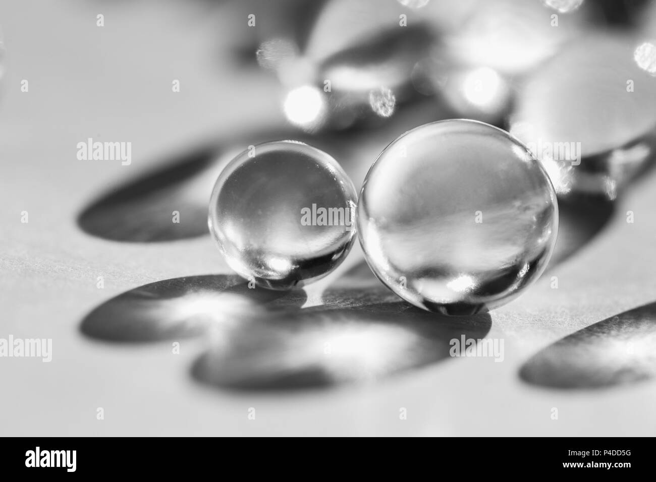 Poco palle di vetro in presenza di luce diretta del sole, macro. Sfondo astratto, foto in bianco e nero Foto Stock