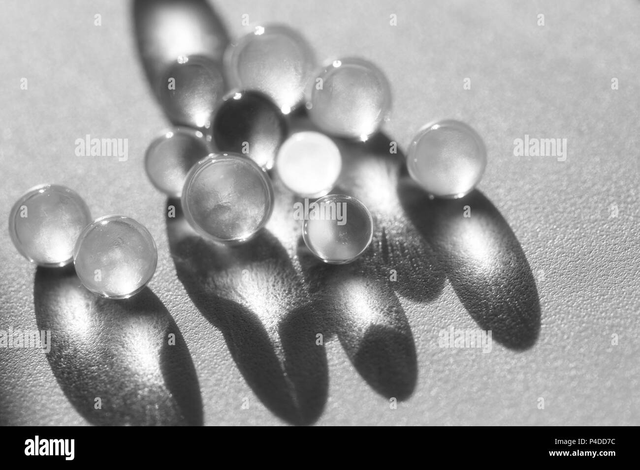 Poco palle di vetro in presenza di luce diretta del sole, macro. Sfondo astratto, foto in bianco e nero Foto Stock