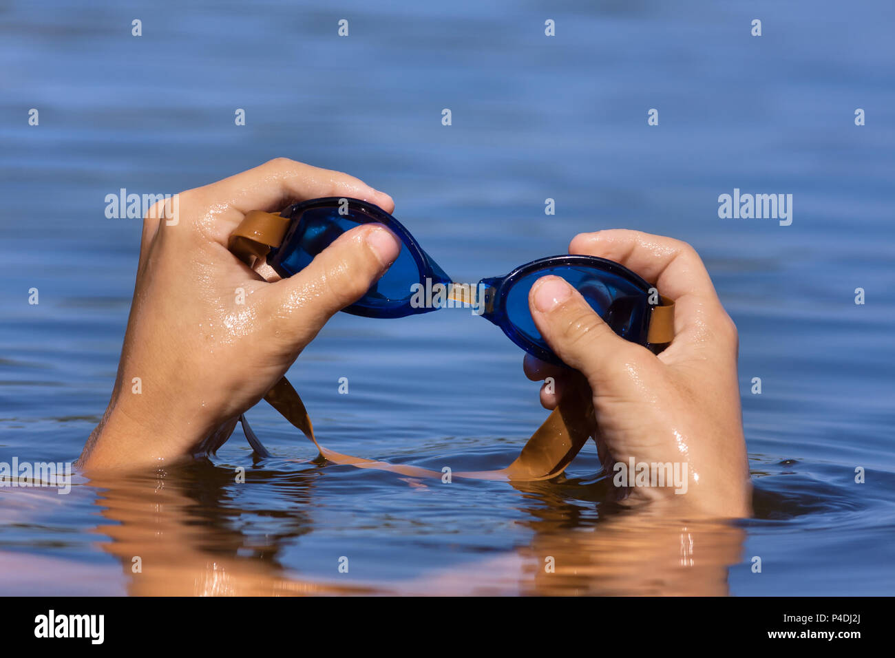 Mano di smimmer tenendo gli occhiali per nuoto sul fondo di acqua Foto Stock