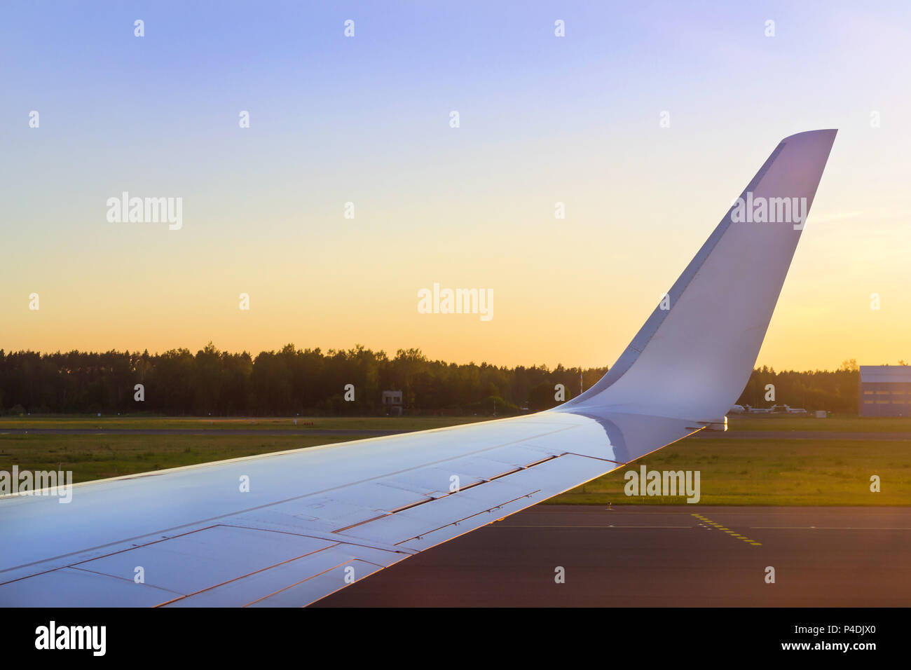 Ala di aerei sopra la pista al tramonto. Aereo passeggeri sulla pista di aeroporto, MARUPE, Riga, Lettonia. Infrastrutture di trasporto stradale internazionale di Foto Stock