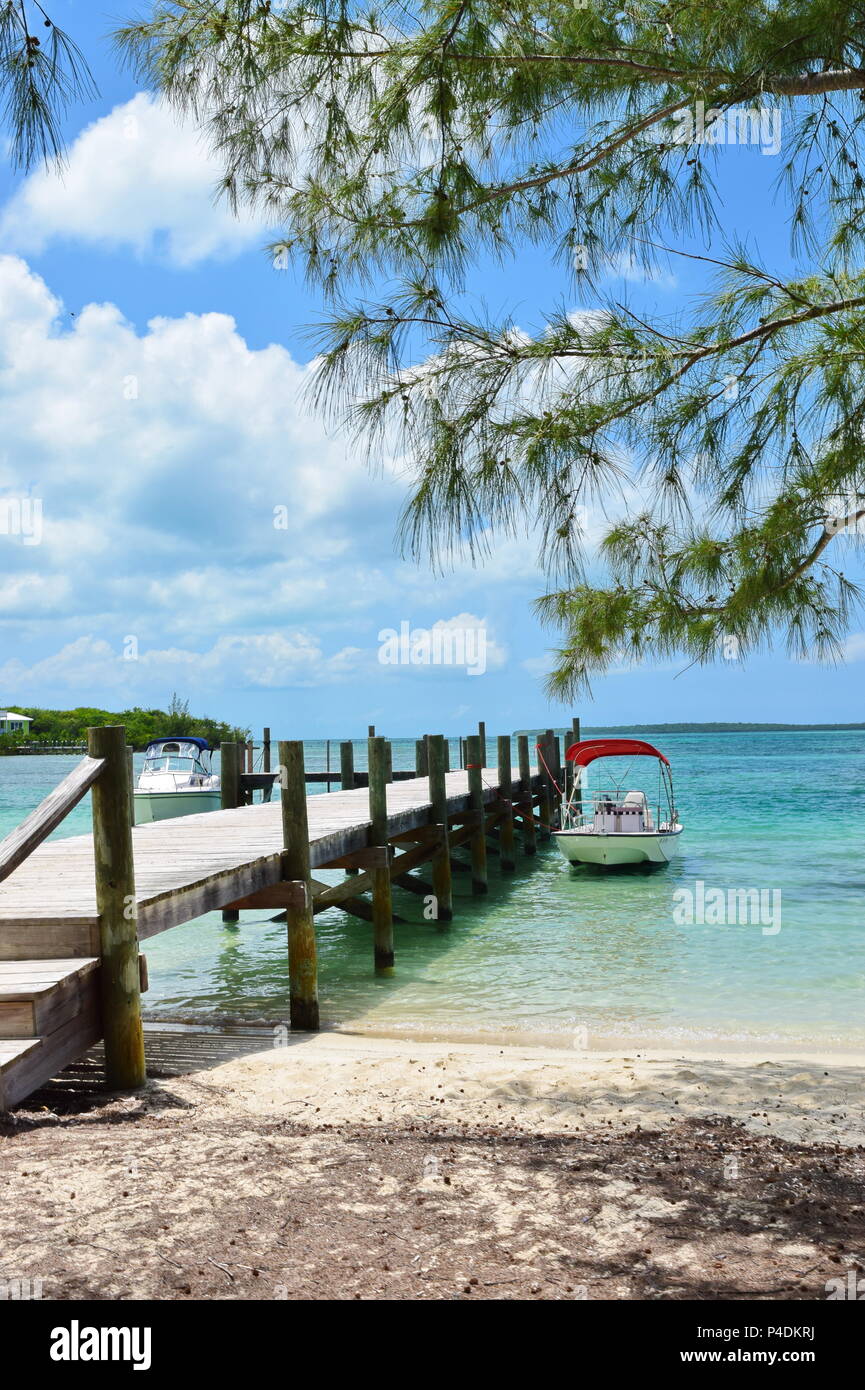 Turtle Bay in Green Turtle Cay in Bahamas. Pier sui Caraibi acque blu e cristalline con barche ormeggiate, gli alberi e le nuvole in cielo. Foto Stock