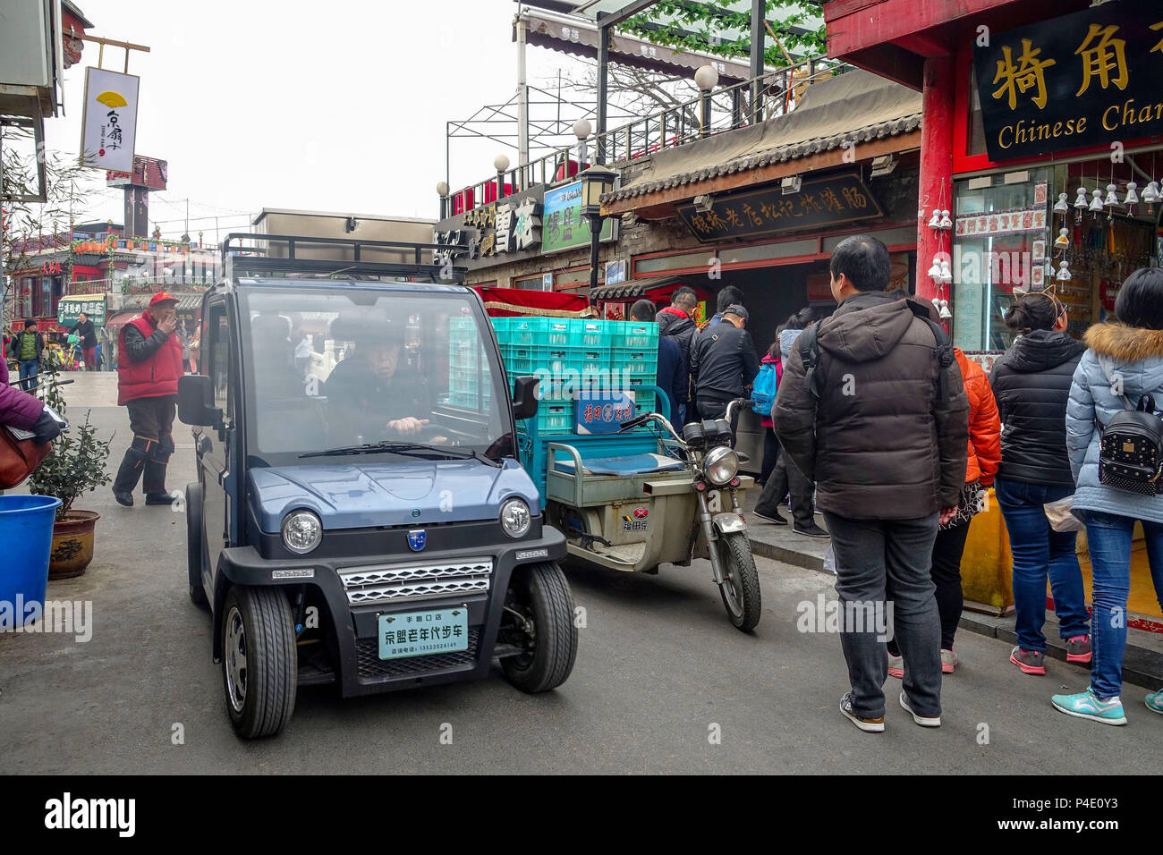 Pechino, Cina - 12 Marzo 2016: la gente guida attraverso le strade con biciclette, scooter e auto. Foto Stock