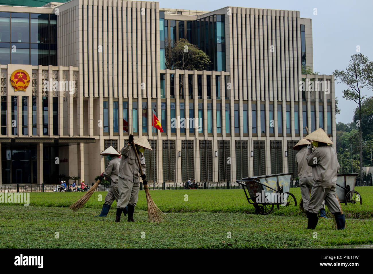 Hanoi, Vietnam - Marzo 15, 2018: pulizia giardinieri l'erba tra il governo vietnamita e costruzione di Ho Chi Min mausoleo Foto Stock