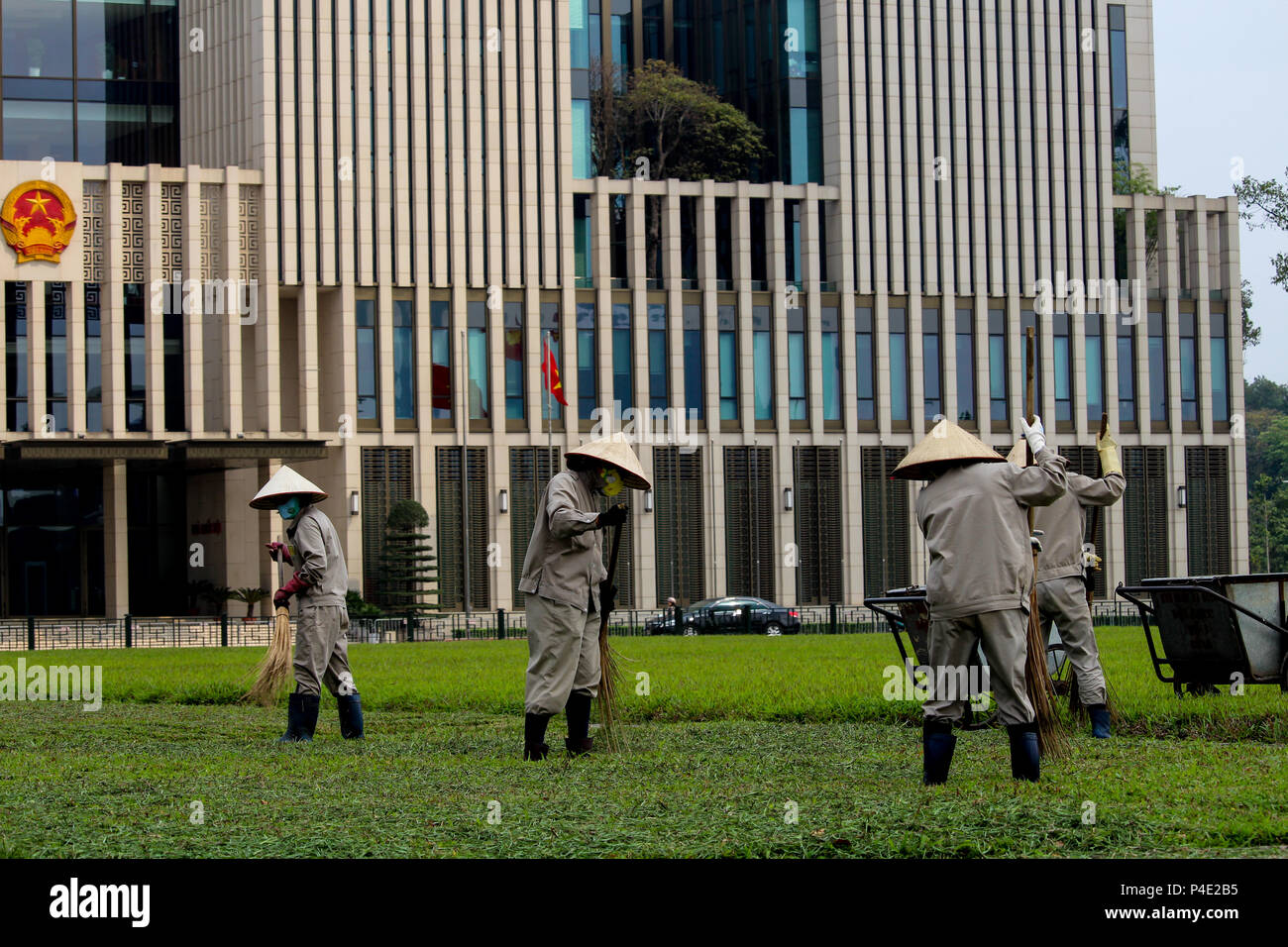 Hanoi, Vietnam - Marzo 15, 2018: pulizia giardinieri l'erba tra il governo vietnamita e costruzione di Ho Chi Min mausoleo Foto Stock